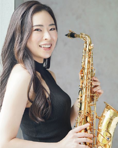 サクソフォンを胸の前で持ち、笑顔を向ける山川 寛子。